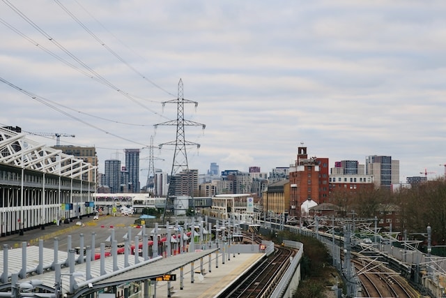 Bild von einem Strommasten in der Stadt und einem Bahnhof nebenan