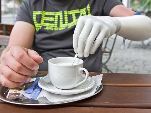 Mann mit Hand-Prothese rührt Kaffee um 