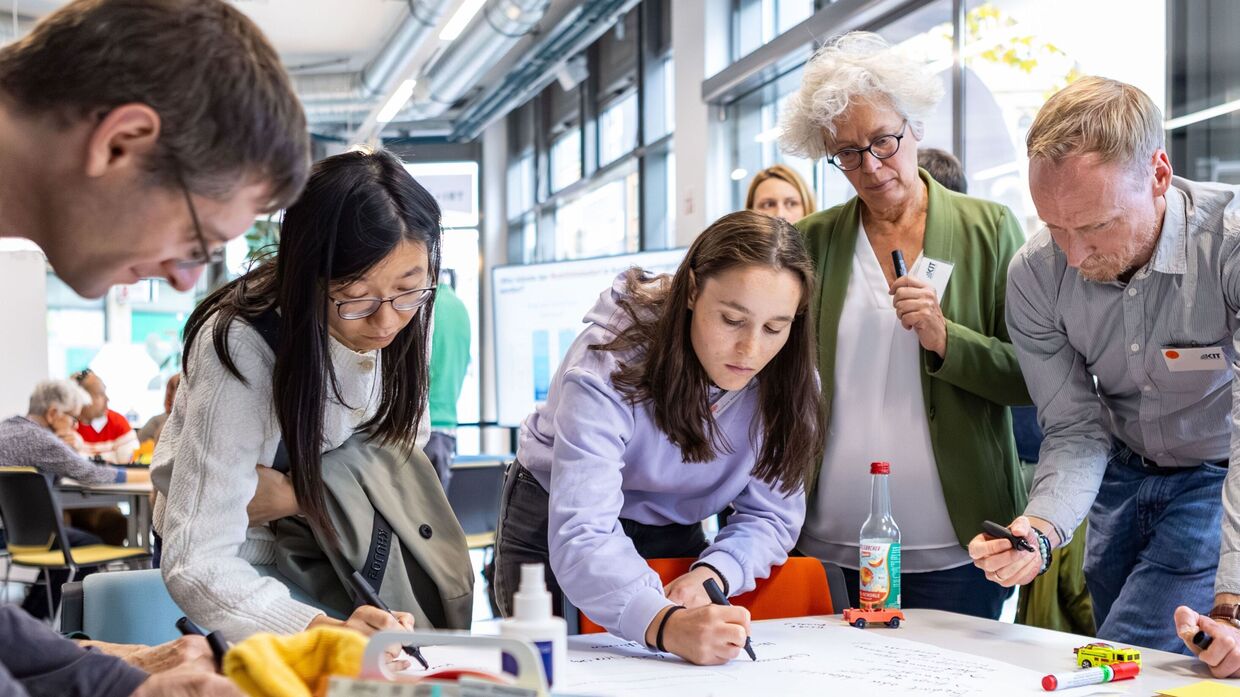 Bürgerinnen und Bürger sitzen an einem Tisch und diskutieren