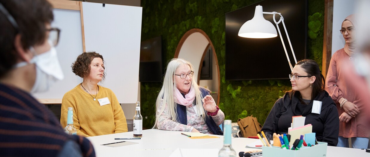 Magali Hauser / KIT Personen bei einer Diskussion an einem runden Tisch in einem modernen Raum.